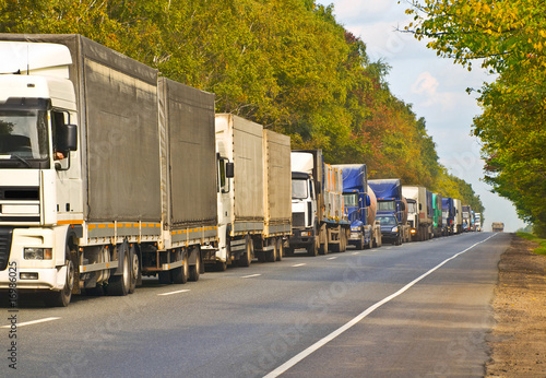 queue of lorry cargo trucks, commercial transports on landscape road