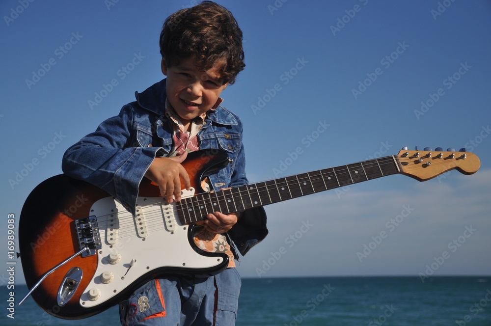 enfant 5 ans qui joue de la guitare électrique fond mer Photos