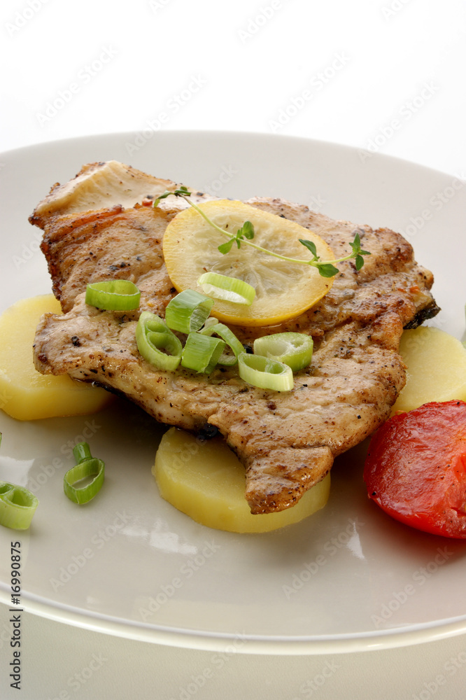 grilled carp fillet on organic potato with lemon and tomato