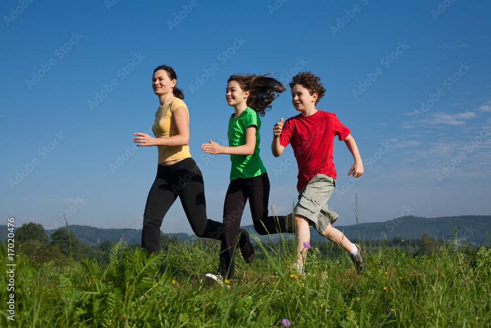 Active family - mother and kids running on green meadow Active family - mother and kids running on green meadow