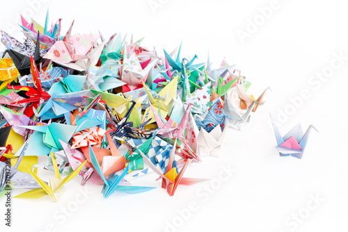 A paper crane standing out from a pile of paper cranes