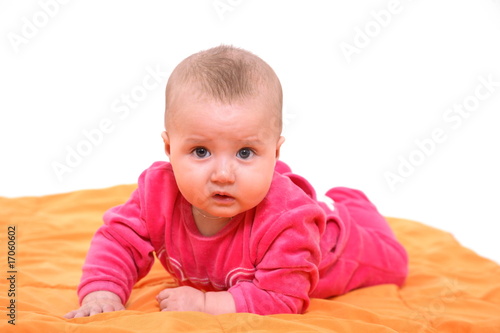 The kid lays on a stomach on an orange background