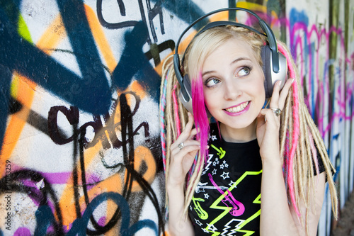 portrait of young woman with headphones at graffitti wall