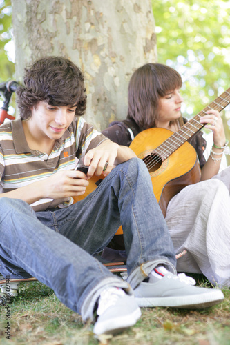 garçon avec téléphone près d'une fille jouant de la guitare