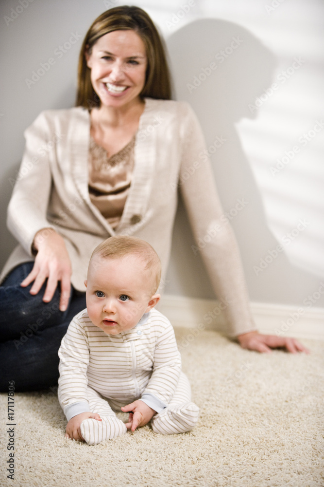 Mother sitting on floor with six month old baby Mother sitting on floor with six month old baby