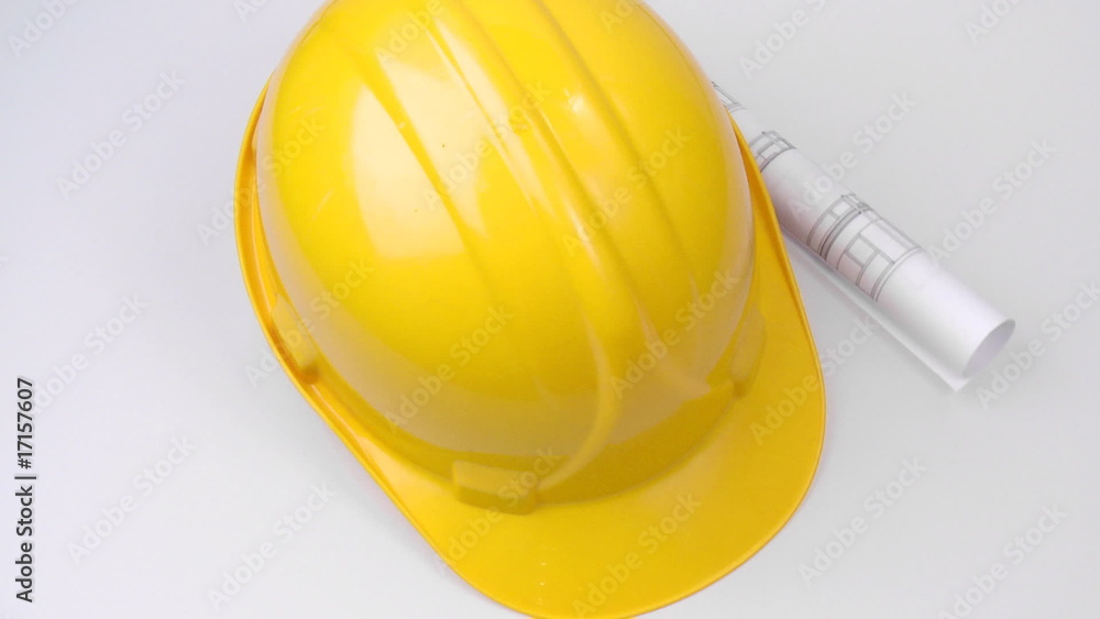 High view of a yellow hard hat and a plan turning