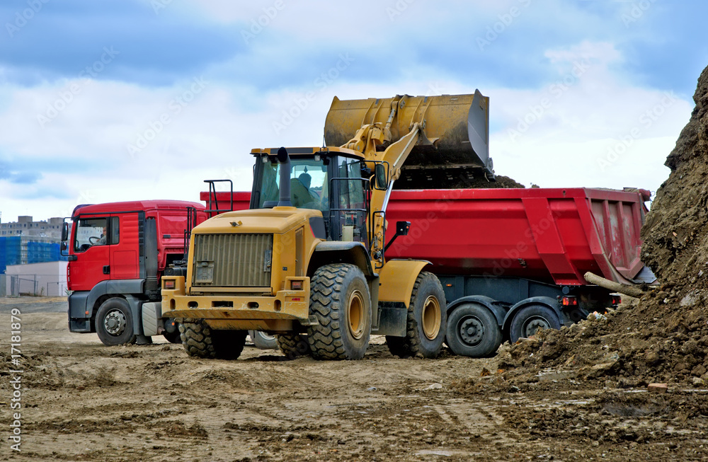 Works in industrial zone. Excavator is loading ground to track Works in industrial zone. Excavator is loading ground to track