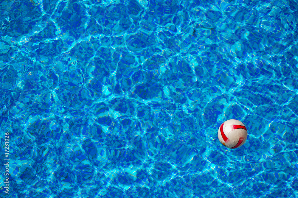 Beach ball floating in swimming pool with mosaic bottom