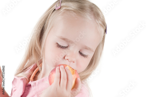 Little girl eating peach in studio