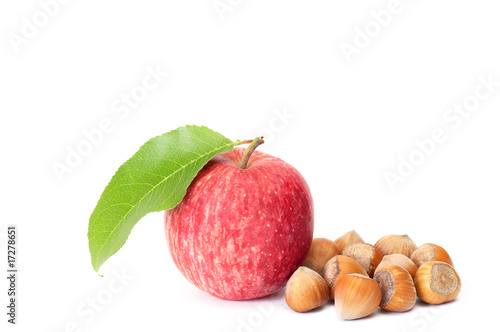 Tasty hazelnuts and fresh apple on a white.
