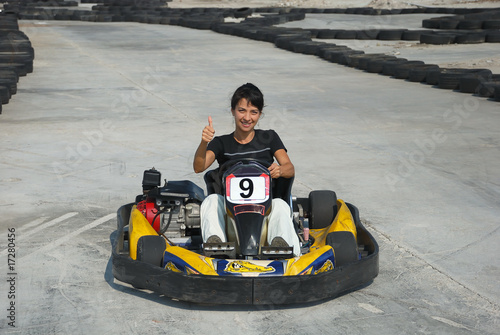 prety brunette driving a kart on karting circuit