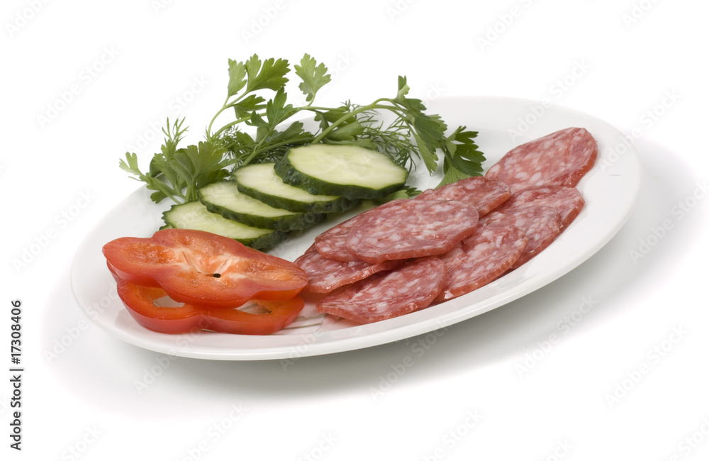 Cut green-stuffs and pieces of sausage on a white dish