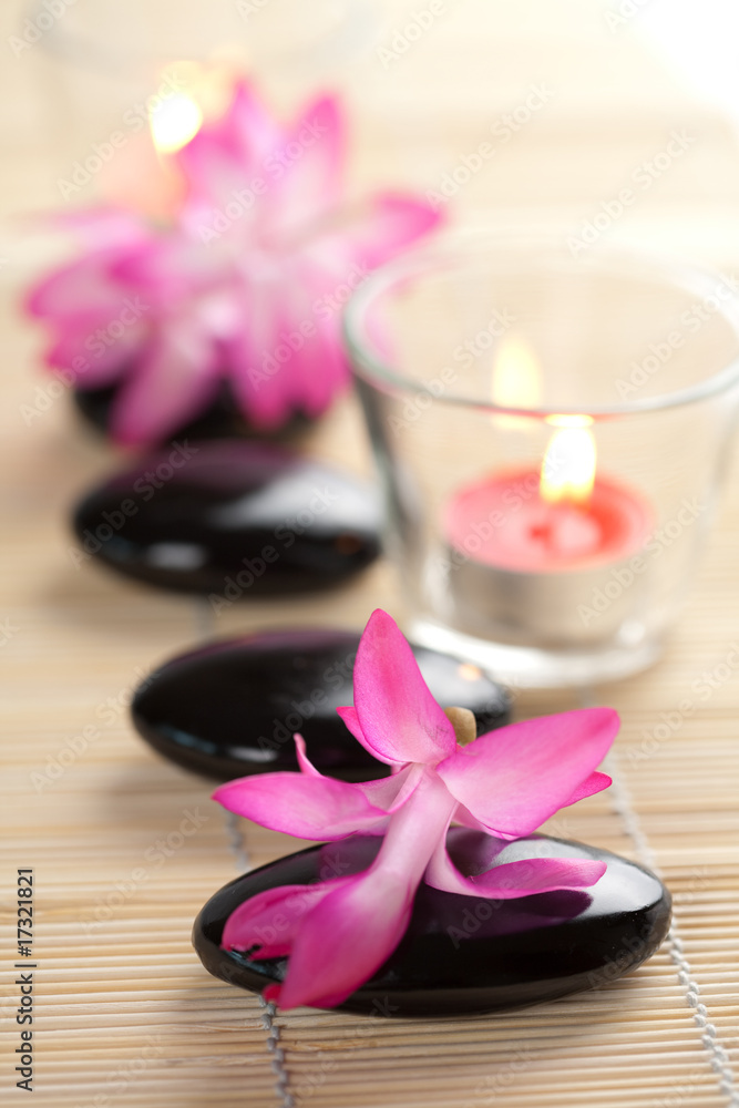 spa stones and pink flowers over bamboo mat