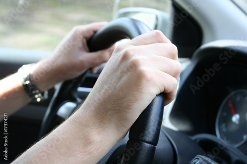 Driver man holds a steering wheel of his car