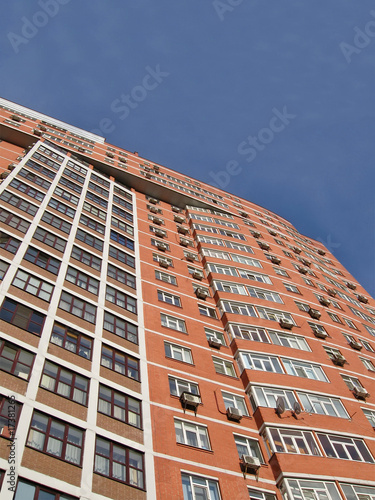 one urban high building, red brown brick, blue sky