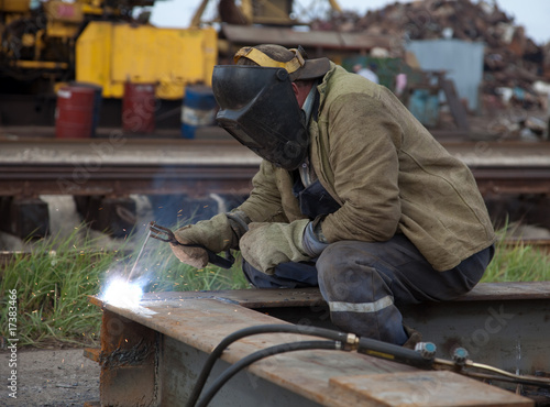 The worker- welder in a protective mask welds metal
