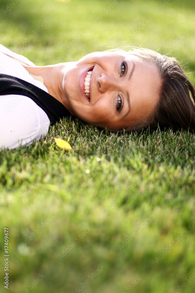 Cute young female lying on grass field at the park . Cute young female lying on grass field at the park .