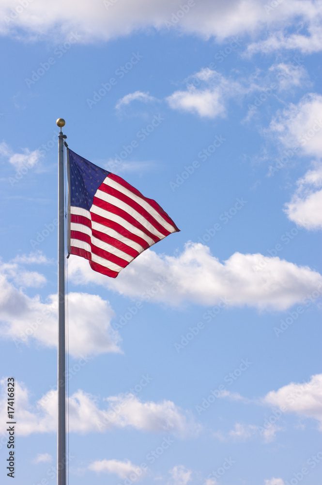 Us Flag waving in the breeze with cumulus clouds in the sky