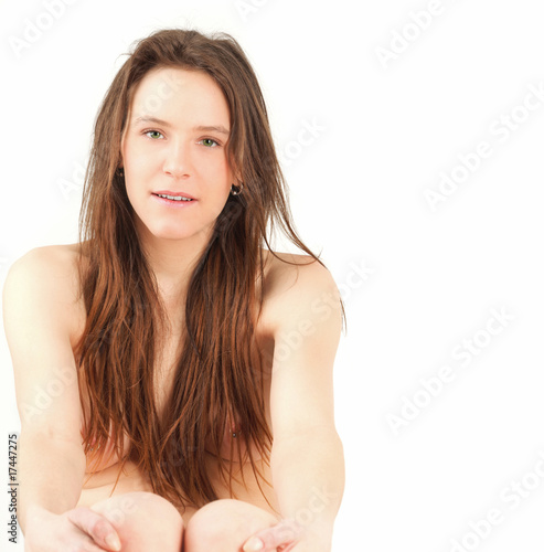 Portrait of young nude woman holding knees, studio shot