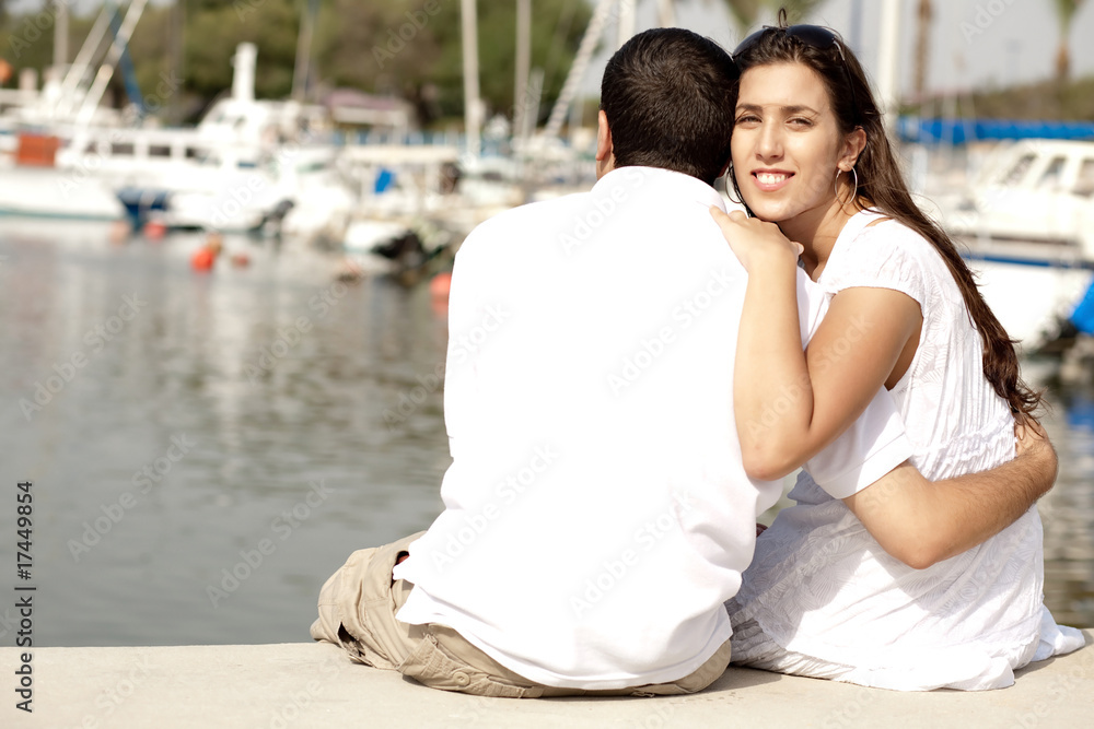Young Couple Seated and Hugging On A Footbridge Young Couple Seated and Hugging On A Footbridge
