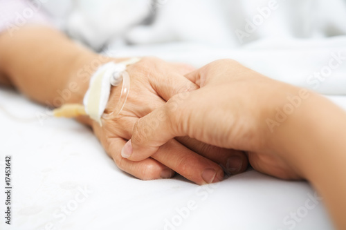 Daughter holding her mother hand in hospital