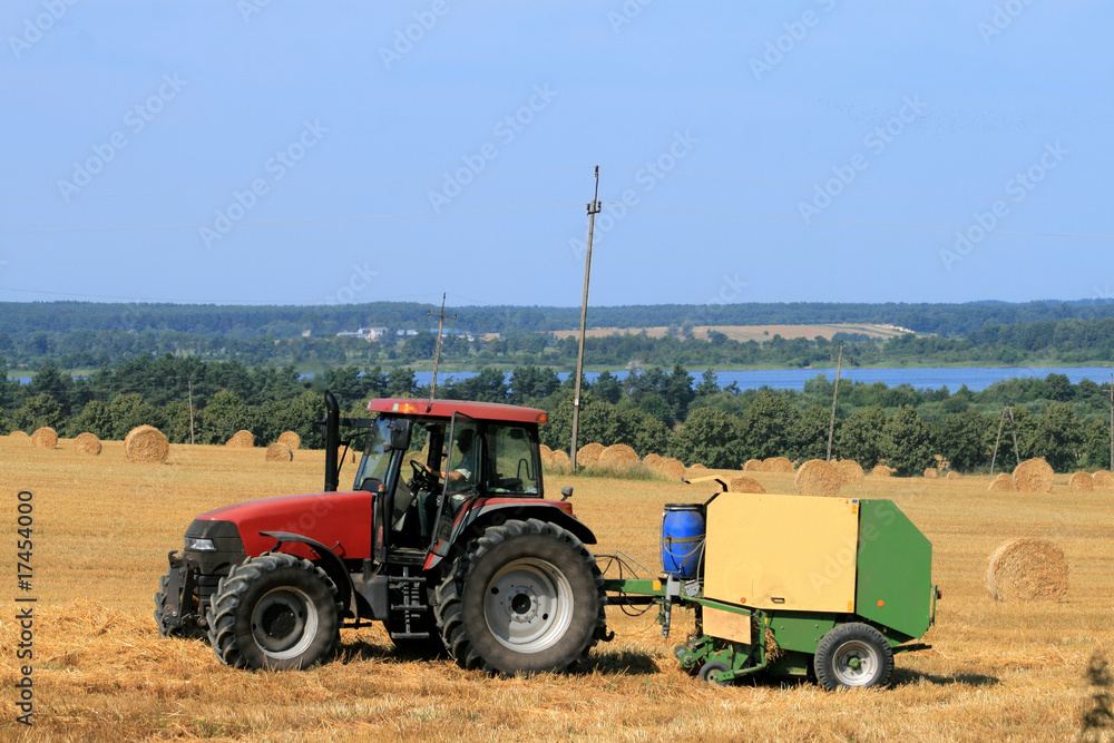 Landscape with tractor, straw bales and a lake Landscape with tractor, straw bales and a lake