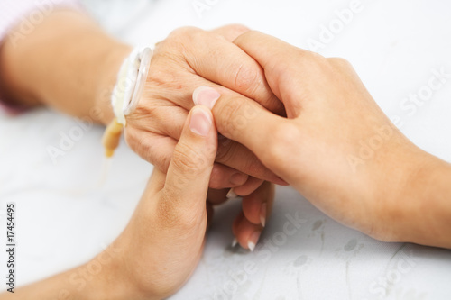 Daughter holding her mother hand in hospital