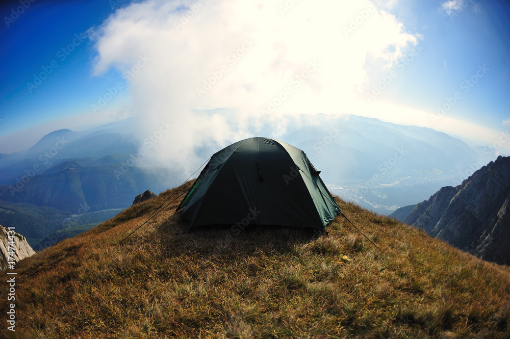 Tent on mountain cliff edge with blue sky