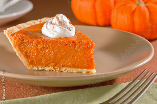 Slice of freshly cut pumpkin pie with whipped cream