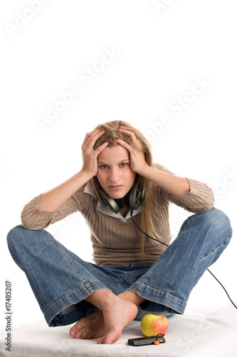 Teenage girl with headache sitting on bed with crossed legs