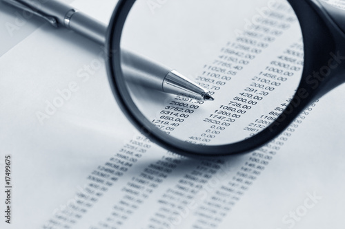 Magnifying glass  and pen over financial report