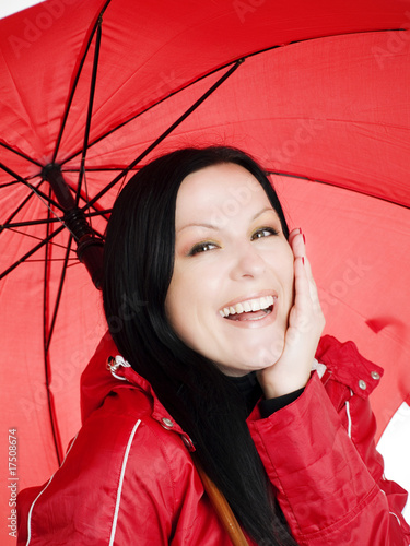 smiling brunette woman in fall, rainproof clothes holding umbrel photo