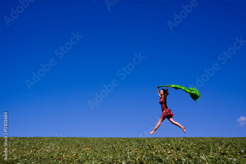 Woman running along a green hill, free in summer photo