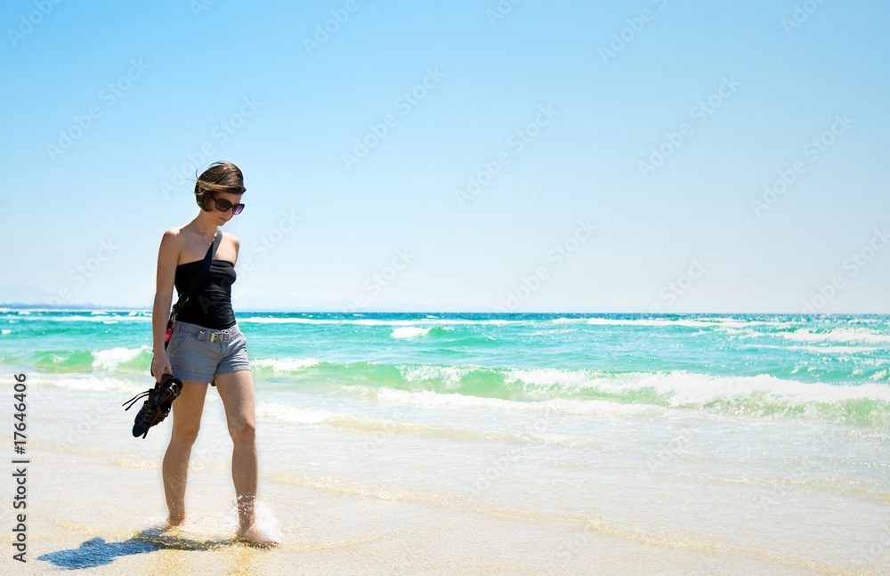 Attractive Brunette Walking Along a Sun Drenched Beach