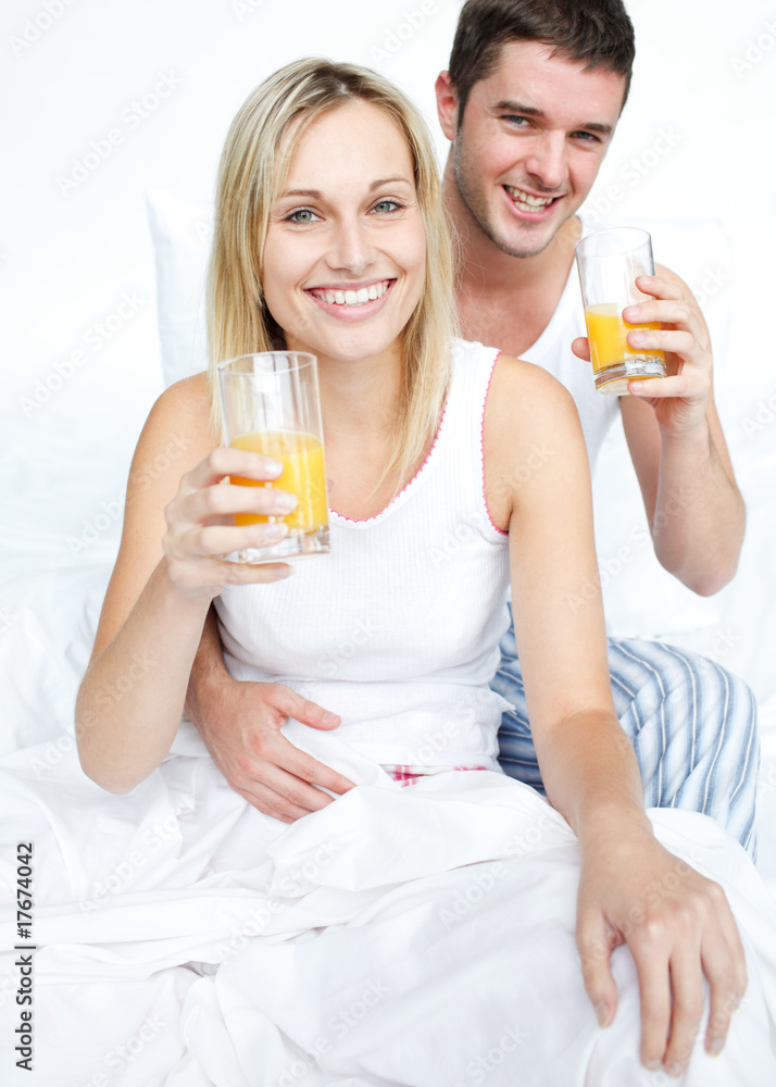 Boyfriend and girlfriend drinking orange juice in bed Boyfriend and girlfriend drinking orange juice in bed