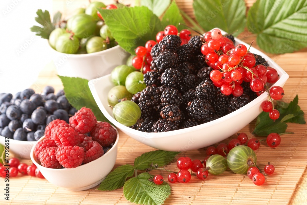 Berries in plates, on a table, among green leaves Berries in plates, on a table, among green leaves