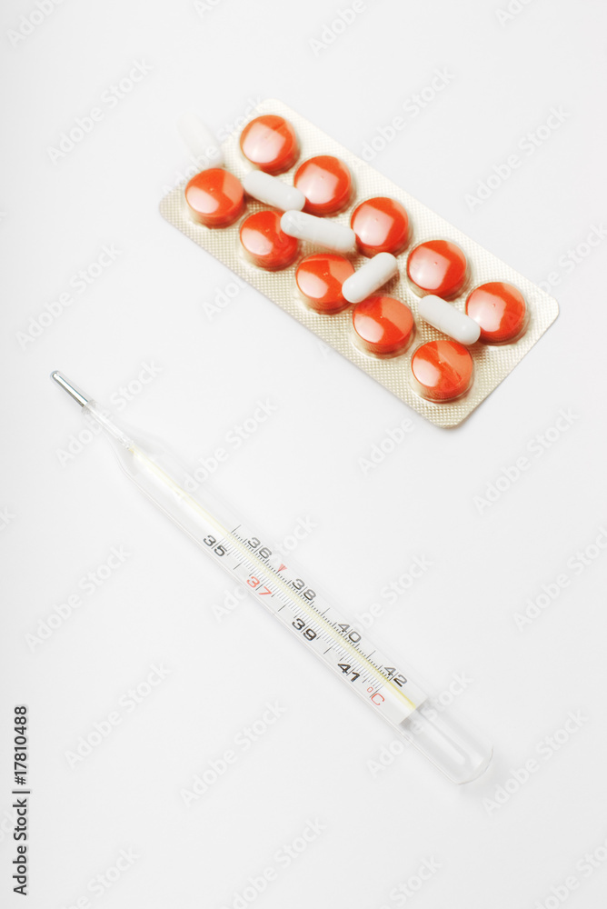 Glass thermometer and pack of red pills and white capsules Glass thermometer and pack of red pills and white capsules