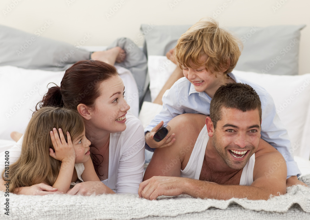 Family lying in bed and son using a remote Family lying in bed and son using a remote