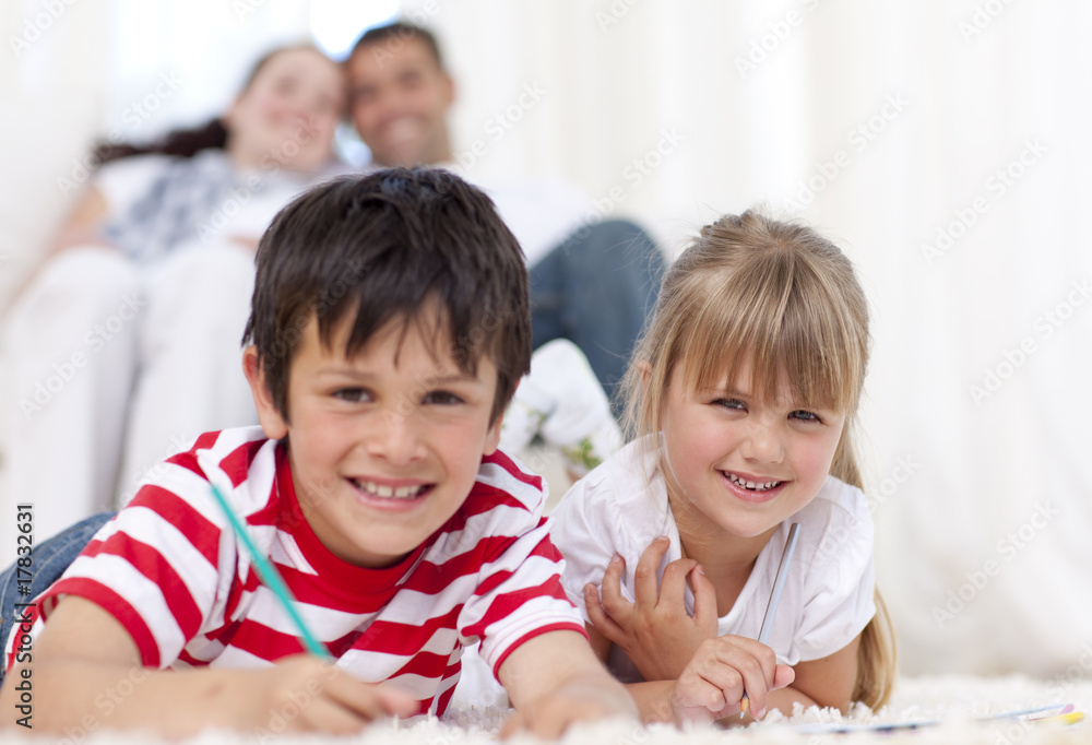 Smiling brother and sister painting on floor in living-room