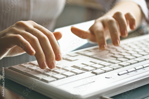 Female hands on the white keyboard.