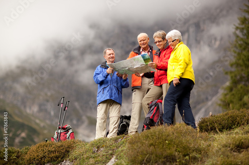 happy senior hiking group looking into map