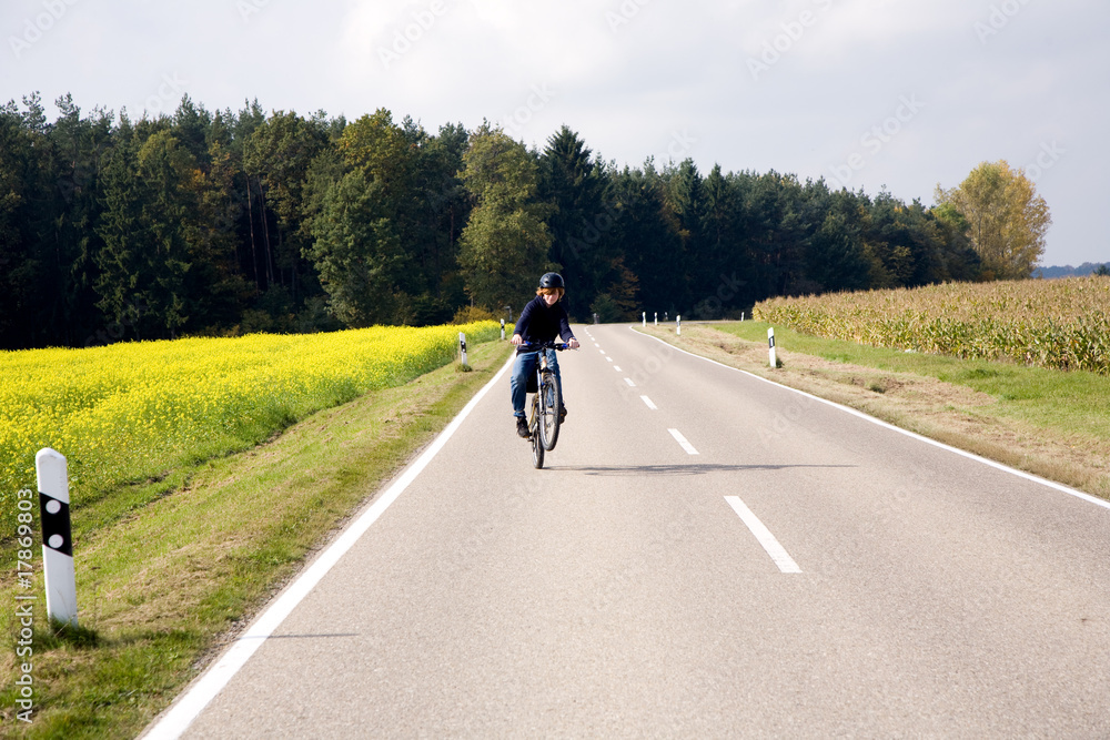 Jugendlicher bei Fahrradtour auf Landstrasse macht Stunts Jugendlicher bei Fahrradtour auf Landstrasse macht Stunts