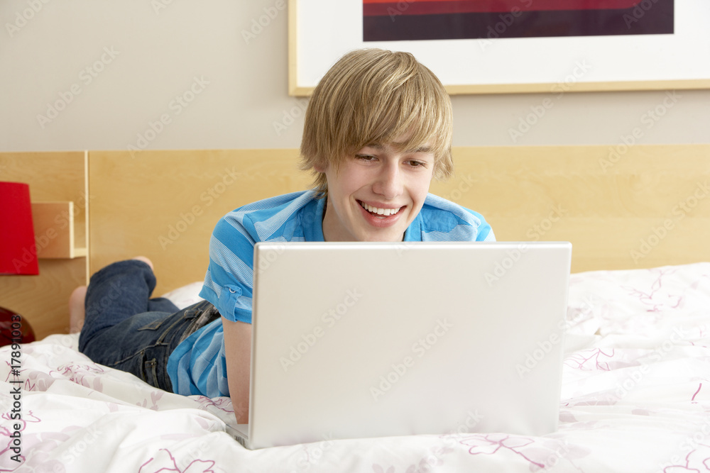 Teenage Boy Using Laptop In Bedroom Teenage Boy Using Laptop In Bedroom