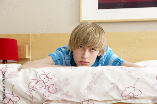 Teenage Boy In Bedroom Looking Sad photo