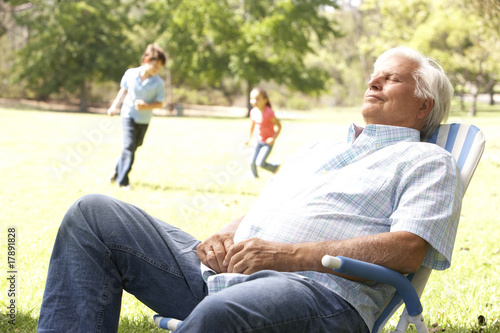 Senior Man Relaxing In Park With Grandchildren In Background © Monkey Business