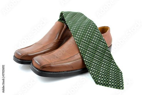 Pair of brown male business shoes and green tie over white photo