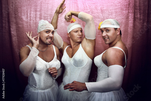 Three strong men in suits of ballerinas. Ñomic photo on a pink b photo