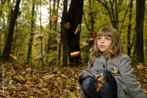 girl playing with flying leaves