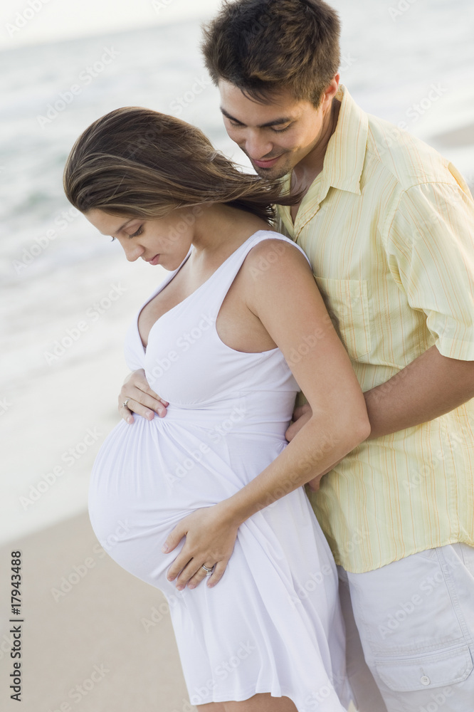 Husband hugging pregnant wife on beach Husband hugging pregnant wife on beach