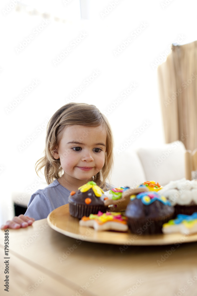 Little girl looking at confectionery at home Little girl looking at confectionery at home